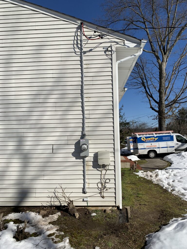 Exterior electrical setup with meter and conduit on a snowy day in Dover, NJ.